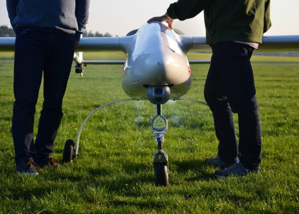 Two people standing behind a drone on a lawn