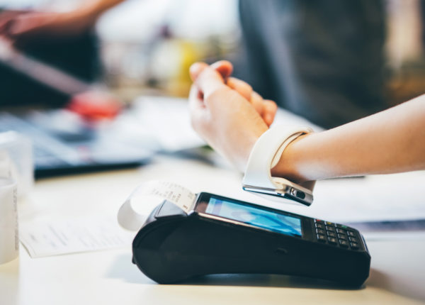 Person holding a smart watch on top of a card machine