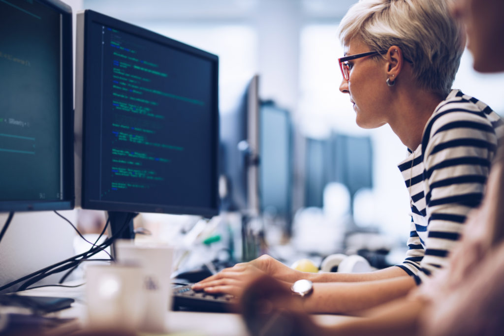 Woman sitting in front of a computer displaying code