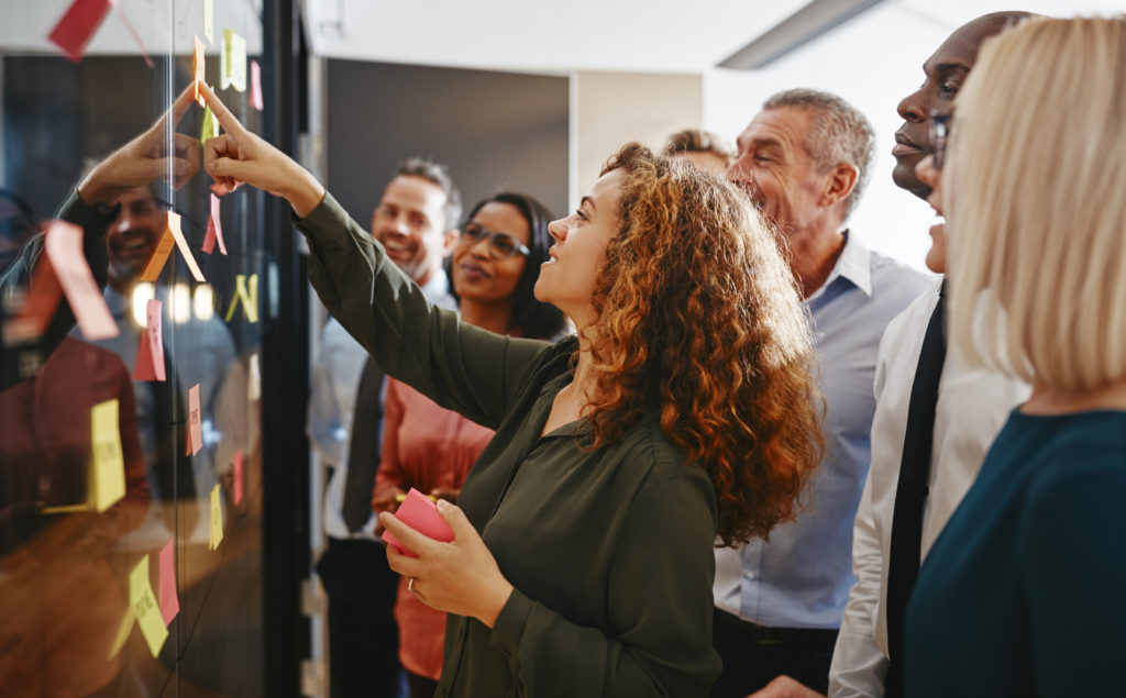 Group of individuals looking at sticky notes on a board