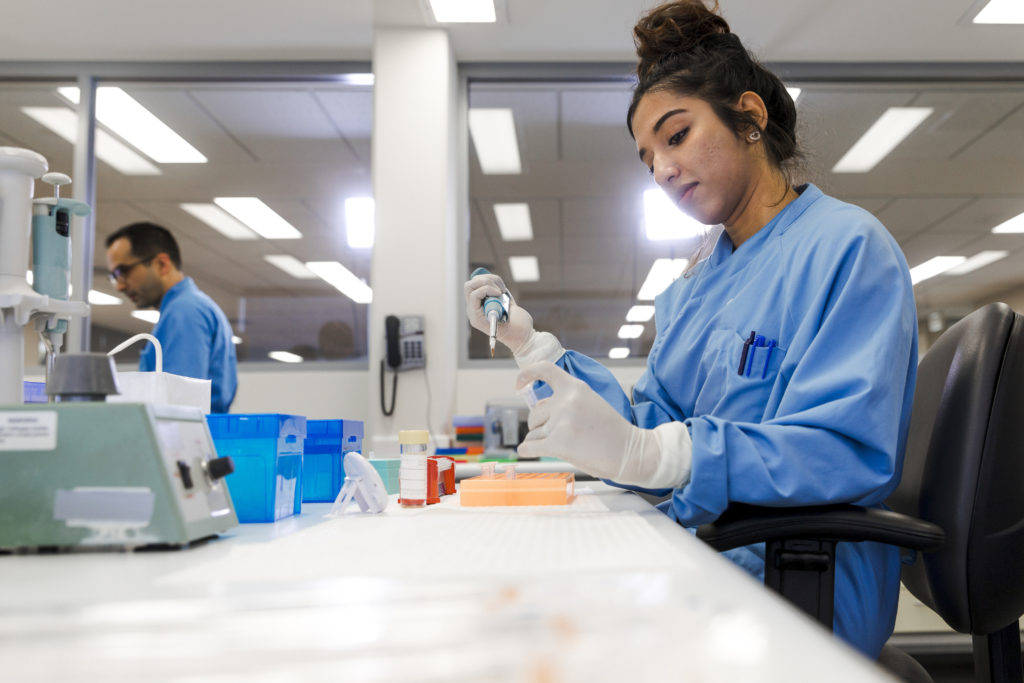 Woman in a lab using a pipette